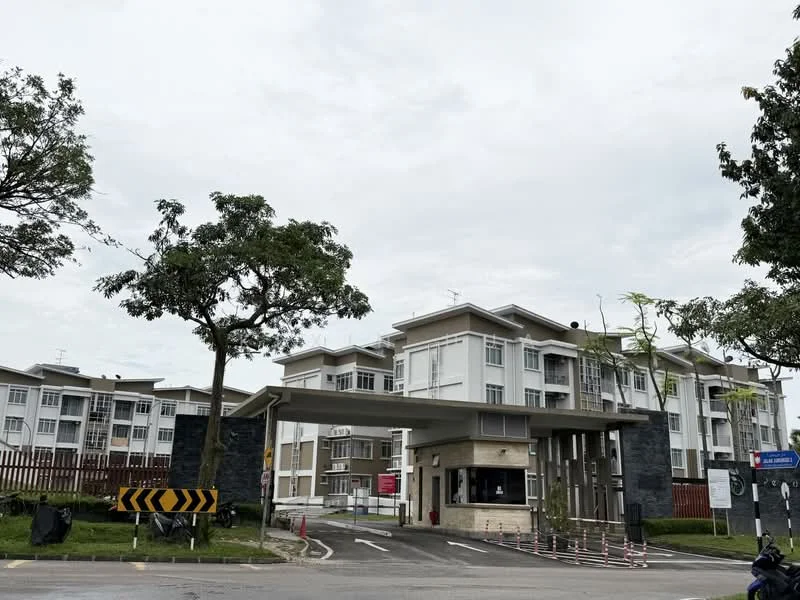 Exterior type: low-rise apartment block; features: white painted facade, stone cladding at entrance, flat roof, double-volume main lobby, manicured lawn, mature trees, security guard house at entrance, perimeter fence, gated entry, parking area with marked spaces, surrounded by greenery; style: modern.