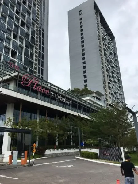 Exterior type: high-rise condominium; features: glass curtain wall, white painted facade, recessed balconies, landscaped garden area, manicured lawn, paved driveway, signage with name 'Place @ Cyberjaya', multiple storeys, modern architectural design; style: modern.