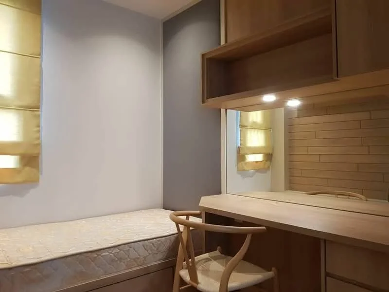 Bedroom features: single bed with mattress, wooden study desk, wooden chair, mirror on desk, built-in cabinetry, yellow sheer curtains, grey accent wall, wood paneling on wall, recessed lighting; style: modern.