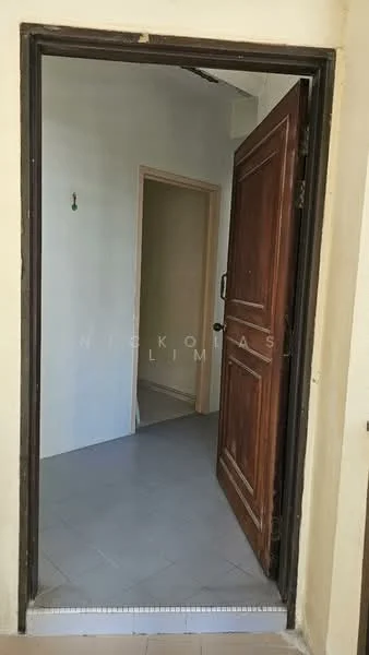 Room features: wooden door, grey tiled flooring, plain white walls, doorway leading to another room.