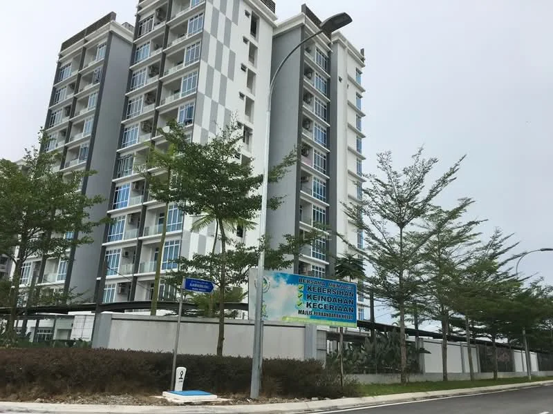 Exterior type: mid-rise condominium; features: grey and white painted facade, balconies with glass railings, approximately 6-storey building, surrounded by landscaped greenery, street lighting, signage visible at the entrance, manicured shrubs, paved walkway; style: modern.