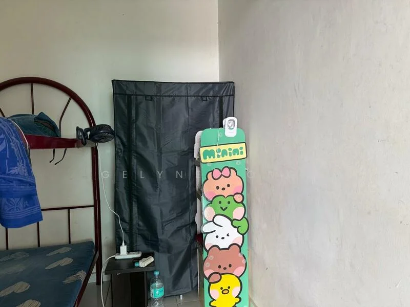 Room features: single bed with red metal frame, blue bedding, black privacy screen, decorative standing board with cartoon characters, white wall, flooring not visible.