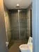 Bathroom features: walk-in shower with glass enclosure, rain shower head, handheld shower, grey tile cladding, modern toilet, recessed ceiling lights, sliding glass door, dark flooring; style: modern.