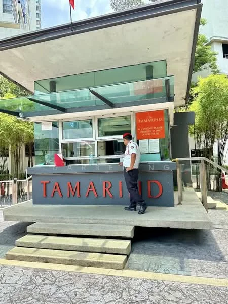 Exterior type: clubhouse; features: modern facade with glass elements, stone-clad entrance, security guard at entrance, outdoor seating area, signage with 'TAMARIND', surrounded by greenery, paved walkway, canopy overhang; style: modern.