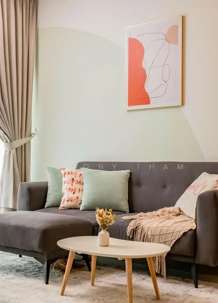 Living features: grey fabric sofa, decorative throw pillows in various colors, round coffee table, area rug, framed abstract artwork on wall, curtains, light green accent wall, beige throw blanket; style: modern.