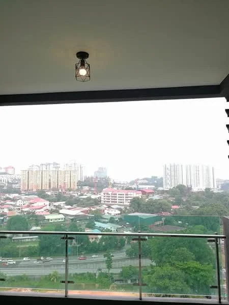 Room features: glass balcony railing, hanging pendant light, concrete ceiling, city skyline view, urban landscape, overhead light fixture; style: modern; view: city.