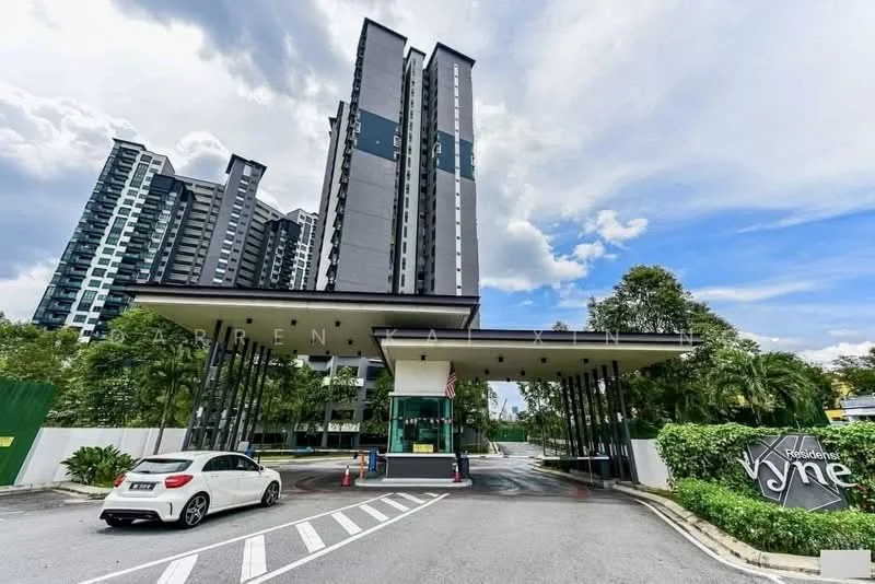 Exterior type: high-rise condominium; features: modern facade with grey and black cladding, multiple storeys, guard house at entrance, landscaped greenery surrounding the entrance, paved driveway, visible parking area, signage for 'Residences Vyne', cloudy sky in background; style: modern.