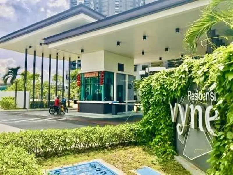 Exterior type: high-rise condominium; features: modern facade with glass and concrete, covered entrance with overhang, landscaped greenery with shrubs, signage with the name 'Residensi vyne', security guardhouse at entrance, paved driveway, surrounded by palm trees, visible high-rise buildings in background; style: modern.
