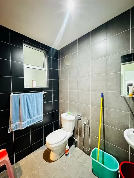 Bathroom features: grey ceramic tile flooring, black tiled walls, white painted walls, one-piece toilet, chrome basin mixer faucet, mirror above sink, window with sheer curtains, towel rack, blue towel, cleaning supplies, bucket, mop, shower hose; style: modern.