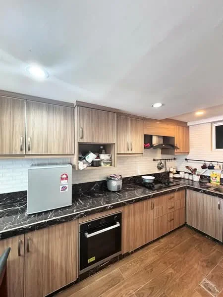 Kitchen features: wood cabinetry in light brown, black marble countertop, white subway tile backsplash, stainless-steel fridge, built-in oven, stainless-steel sink, chrome pull-down faucet, recessed LED downlights, dark wood flooring, microwave, cooking utensils on countertop, open shelving; style: modern.