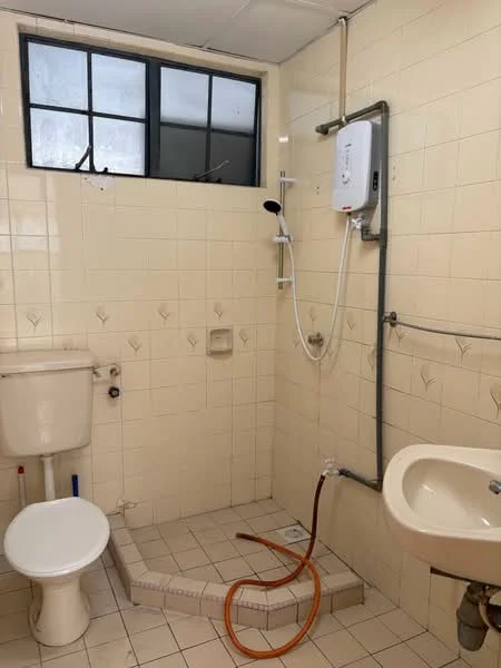 Bathroom features: white tiled walls, cream tiled flooring, shower area with glass partition, wall-mounted shower head, handheld shower, toilet, sink with faucet, window for natural light, exposed plumbing, shower drain, soap holder.
