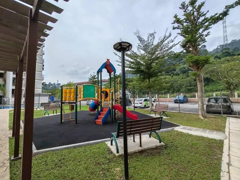 Exterior type: landscape garden; features: children's playground with slides and climbing structures, rubberized safety flooring, park benches, landscaped grass area, trees providing shade, paved walkway, outdoor lighting, fenced perimeter; style: modern.