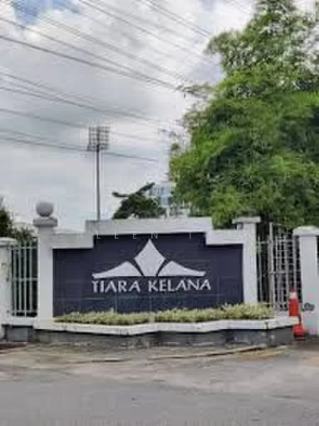 Exterior type: main entrance gate; features: signage with 'Tiara Kelana', stone-clad base, metal gate, surrounding greenery, paved driveway, street lighting, fence, visible power lines, nearby sports field lighting; style: modern.