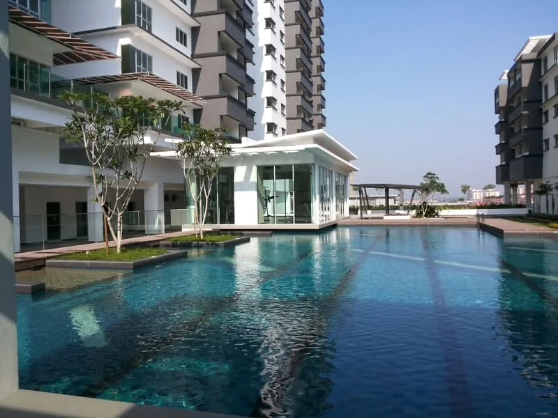 Exterior type: high-rise condominium; features: infinity pool, pool deck with loungers, landscaped garden, glass pavilion, manicured lawn, surrounded by greenery, modern architectural design, multiple storeys, balconies on upper floors; style: modern.