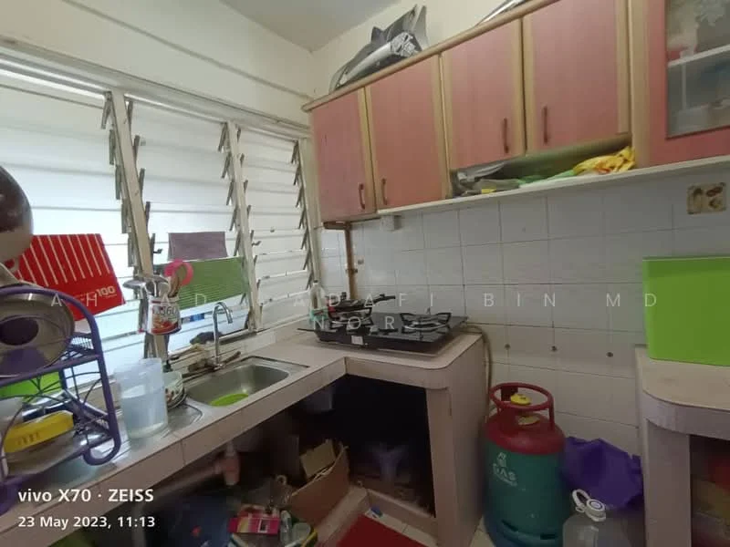 Kitchen features: single-bowl stainless-steel sink, chrome pull-down faucet, 4-burner gas hob, white tiled backsplash, pink cabinetry, countertop with storage space, window with horizontal slats, kitchen appliances visible, gas cylinder, cluttered countertop.