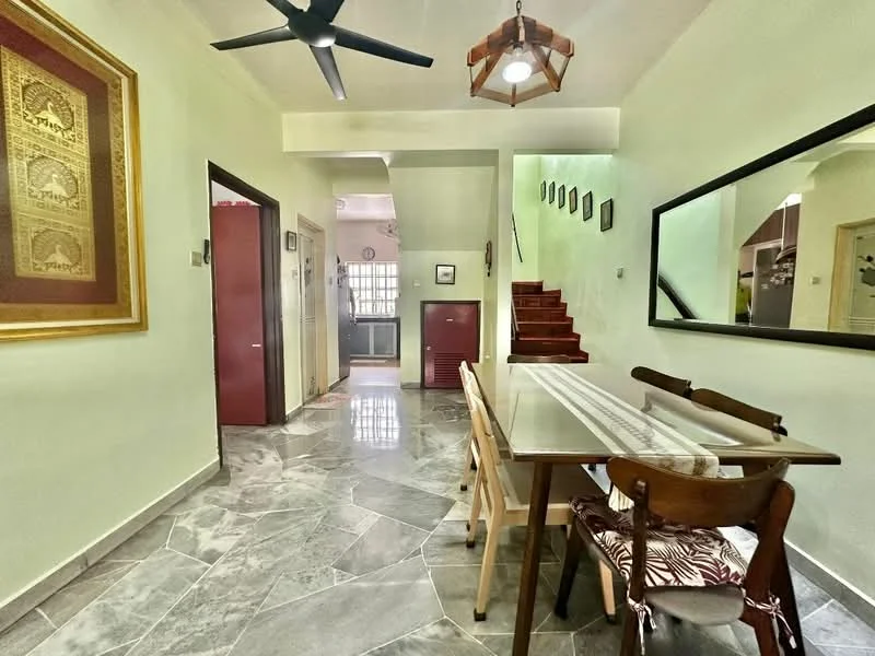 Dining features: rectangular dining table with white tabletop, wooden dining chairs, decorative wall mirror, ceiling fan, pendant light fixture, marble flooring, cream painted walls, staircase visible in background, framed artwork on wall, open layout to living area, natural light from window; style: modern. Room features: cream painted walls, marble flooring, staircase leading to upper level, doorway to kitchen area, decorative wall art.
