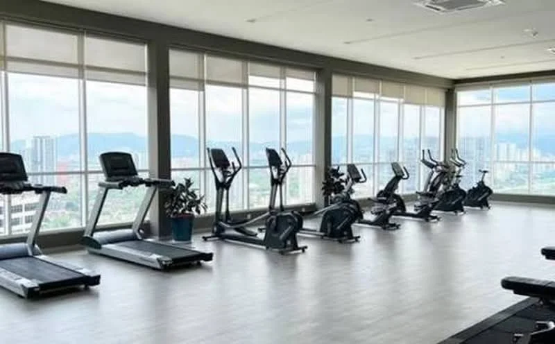 Room features: large windows with city view, wooden laminate flooring, treadmills, elliptical machines, stationary bikes, potted plants, brightly lit space, high ceiling, air conditioning units; style: modern; view: city.