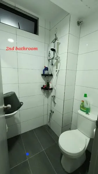 Bathroom features: white tiled walls, grey ceramic tile flooring, shower with handheld showerhead, wall-mounted shower valve, toilet with tank, shelf for toiletries, cleaning supplies on shelf, window for natural light; style: modern.