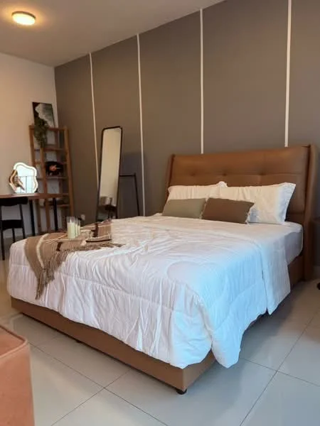 Bedroom features: king-size bed with beige upholstered headboard, white bedding with decorative pillows, light grey accent wall, white painted walls, floor-to-ceiling mirror, wooden shelving unit, study desk with chair, table lamp, decorative candles, tile flooring, recessed ceiling light; style: modern.