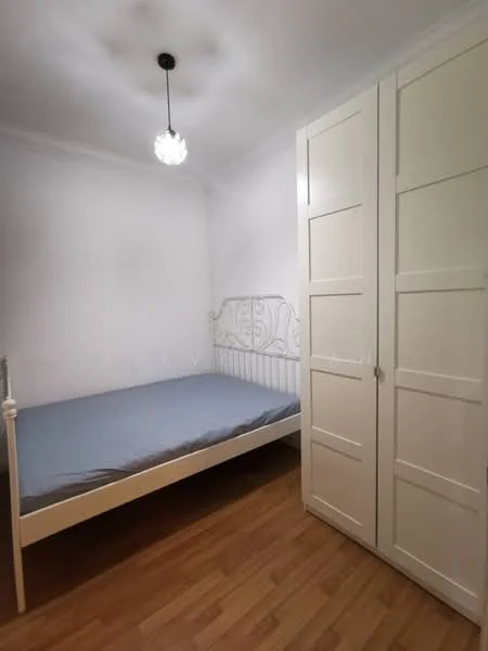 Bedroom features: single bed frame with mattress, white painted walls, wooden flooring, built-in wardrobe with sliding doors, pendant light fixture, window with no visible treatment; style: minimalist.