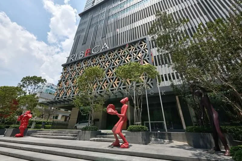 Exterior type: high-rise condominium; features: glass curtain wall, exposed concrete facade, decorative wooden lattice, red sculptures in front, landscaped steps, manicured greenery, signage on building, modern architectural design; style: modern.