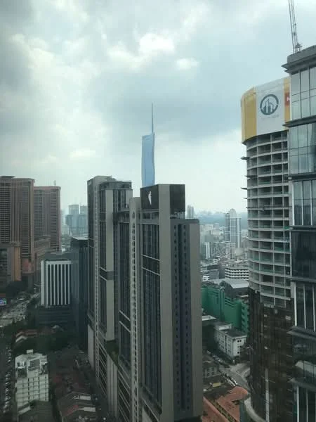 Exterior type: high-rise condominium; features: glass curtain wall, modern architectural design, surrounded by urban skyline, visible cityscape, prominent landmark in background, mixed-use development, high-rise buildings with varying heights; style: modern.