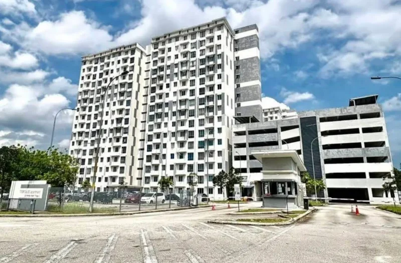 Exterior type: mid-rise condominium; features: white painted facade, grey accent panels, glass windows, multiple storeys, parking deck visible, security guardhouse at entrance, landscaped area with trees, driveway with interlocking pavers; style: modern.