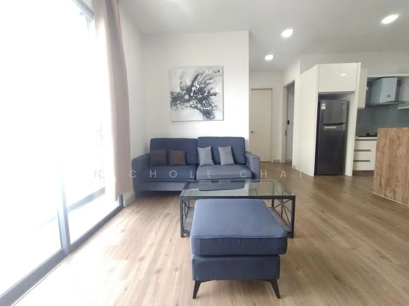 Living features: 3-seater fabric sofa in navy blue, coffee table with black metal frame, wooden flooring, large floor-to-ceiling windows, curtains, abstract wall art, refrigerator visible in background, open kitchen layout, neutral painted walls, light ceiling with recessed lighting; style: modern; view: city.