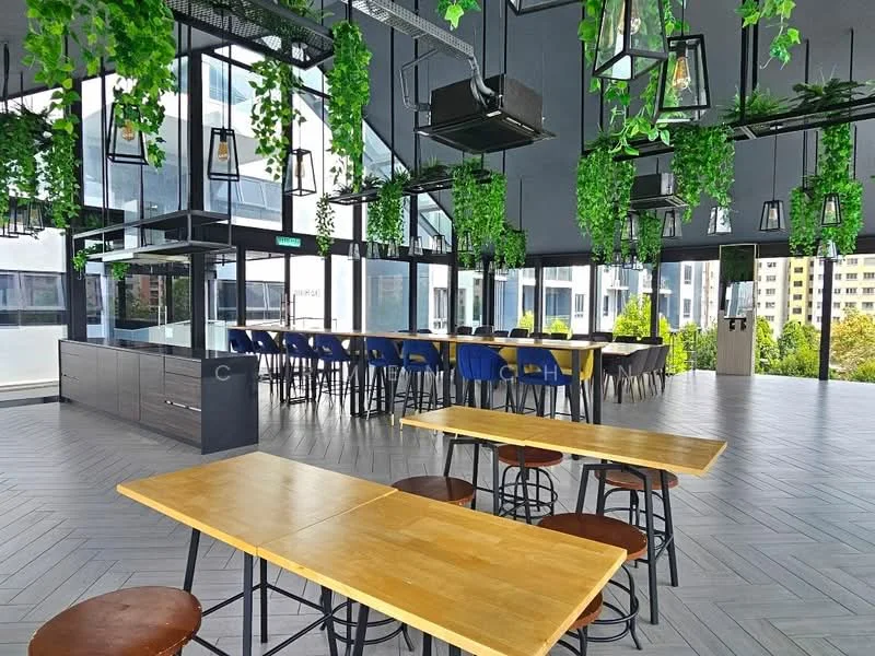Room features: large windows with city view, herringbone patterned flooring, hanging pendant lights, greenery decor with hanging plants, long communal table with wooden surface, blue and black upholstered chairs, open layout, modern design, high ceiling, air conditioning vents, glass partitions; style: modern; view: city.