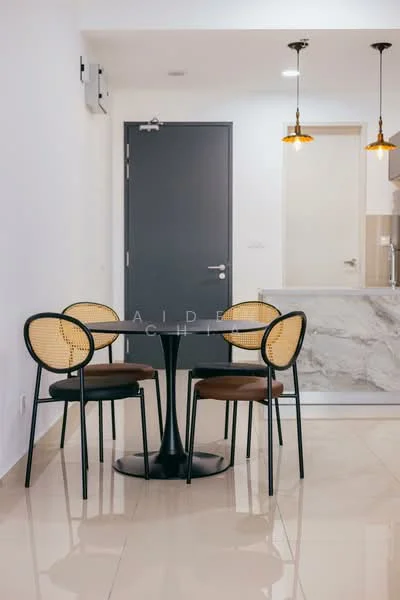 Dining features: round dining table with black base, 4 rattan dining chairs with black frames, pendant lights with warm glow, white painted walls, glossy beige tile flooring, kitchen counter with marble finish, doorway leading to kitchen, door with grey finish; style: modern.