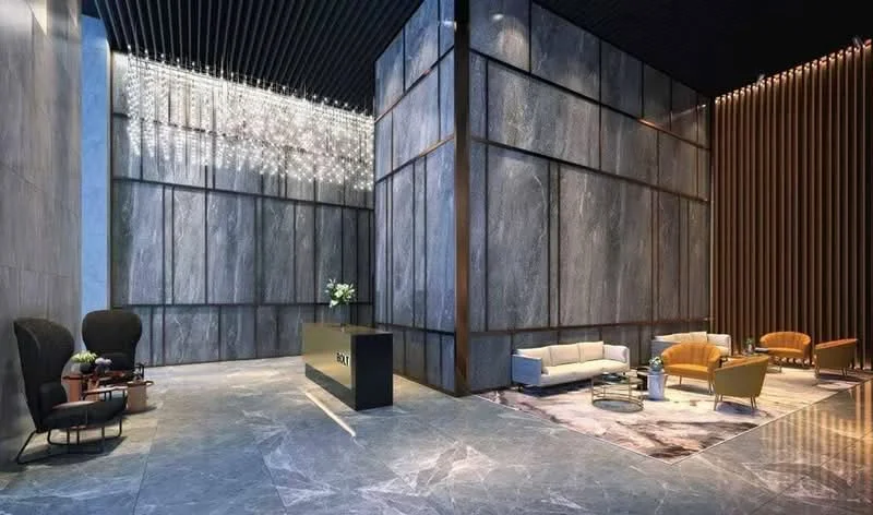 Lobby features: marble flooring, high ceiling, chandelier lighting, grey stone accent walls, wood paneling, reception desk, upholstered armchairs, sofa, coffee table, area rug, decorative plants; style: modern.