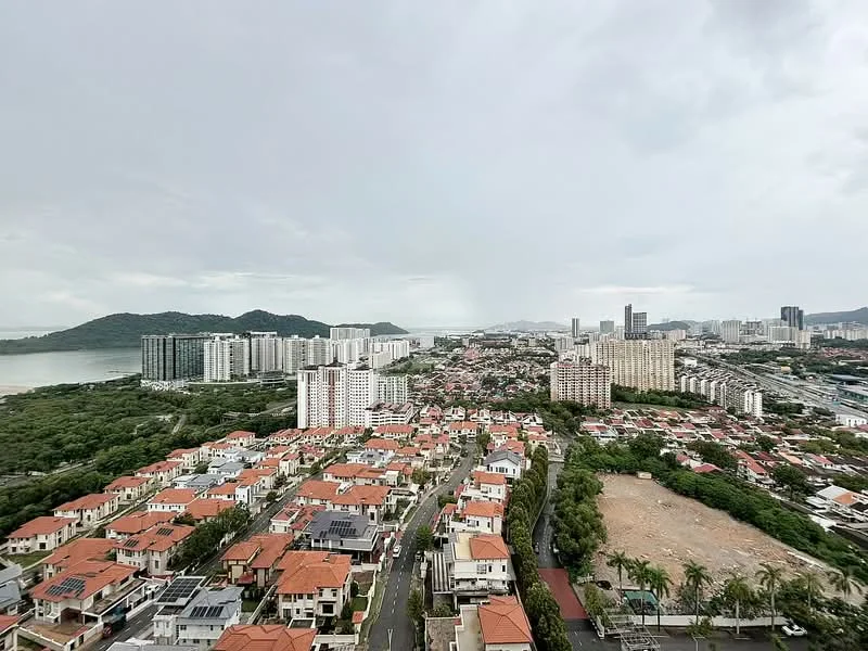 Exterior type: high-rise condominium; features: city skyline view, surrounded by greenery, mixed residential and commercial buildings, rooftop gardens on some buildings, mountainous backdrop, waterfront view, multiple high-rise structures, low-rise houses with red tiled roofs, paved roads, palm trees lining the streets; style: modern.