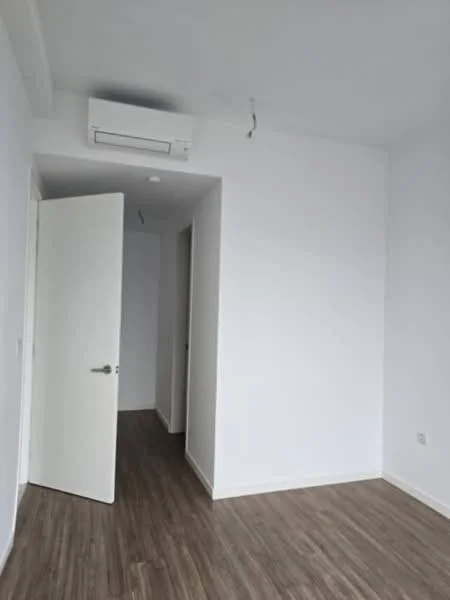 Room features: white painted walls, laminate flooring, 1 wall-mounted split AC, white door, light fixture wiring visible; style: modern.