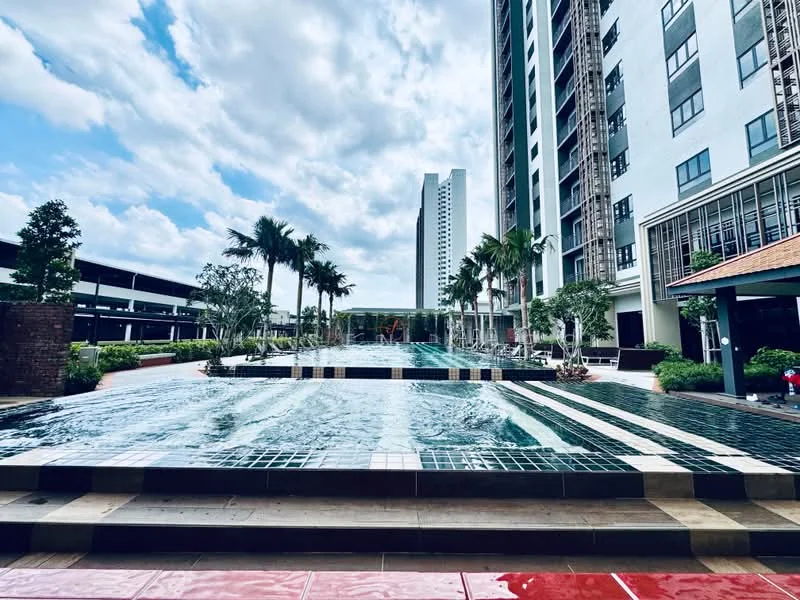Exterior type: high-rise condominium; features: infinity pool, pool deck with loungers, landscaped garden, mature palm trees, manicured lawn, surrounding high-rise buildings, parking deck, water feature, outdoor seating area; style: modern.