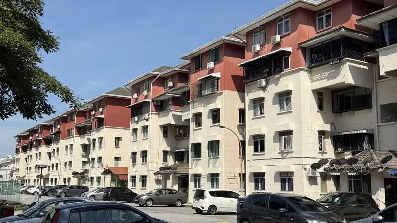 Exterior type: low-rise apartment block; features: red painted facade, cream painted facade, balconies with railings, multiple air conditioning units, visible parking spaces, surrounded by trees, street view, multiple storeys; style: modern.
