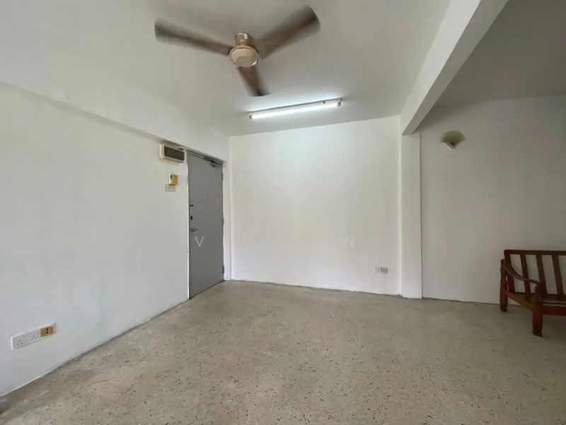 Living features: white painted walls, concrete flooring, ceiling fan, wall-mounted light fixture, single wooden chair, door to entrance, window, no visible decor.