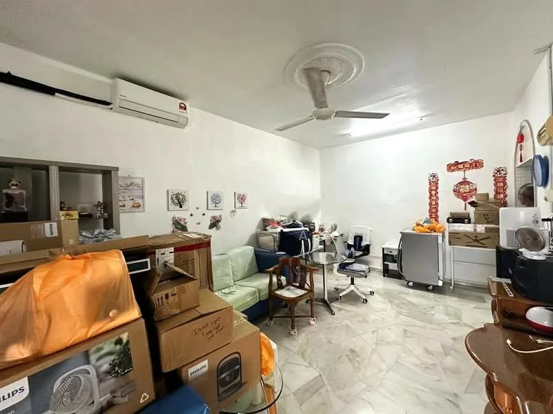 Room features: white painted walls, marble flooring, 5-blade ceiling fan, 1 wall-mounted split AC, various cardboard boxes, green fabric sofa, wooden chair, office desk, plastic storage containers, decorative wall art, small white cabinet.