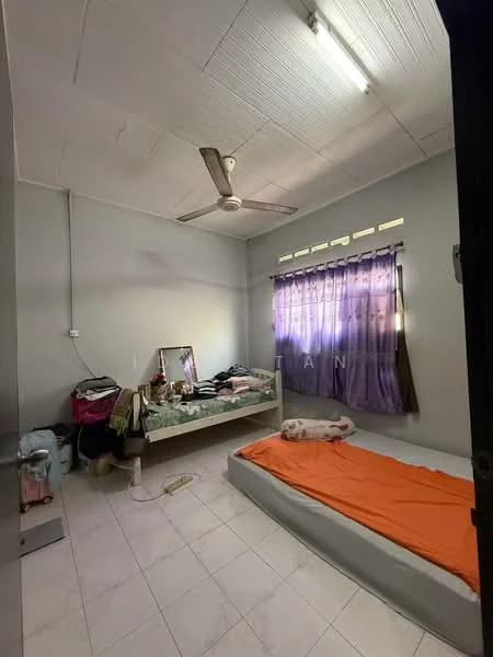 Bedroom features: single bed, double bed, ceiling fan, white painted walls, tile flooring, window with sheer curtains, mirror on dresser, orange bedspread, clothes on bed, clothes on floor, light fixture on ceiling.