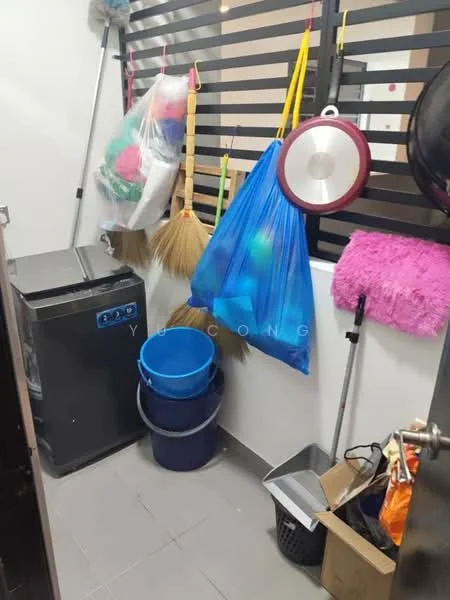 Laundry features: front-load washing machine, grey plastic bucket, blue plastic bucket, broom, mop, pink cleaning cloth, hanging storage bags, black trash bin, grey tiled flooring, slatted wall panel.