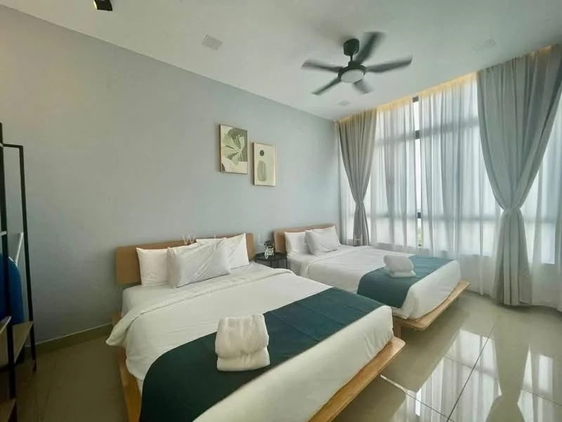 Bedroom features: two queen-size beds, white bedding with decorative throw pillows, wooden bed frames, light grey painted walls, large floor-to-ceiling windows, sheer curtains, dark green bed runner, ceiling fan with light, polished tile flooring, framed artwork on walls, nightstands with lamps; style: modern.