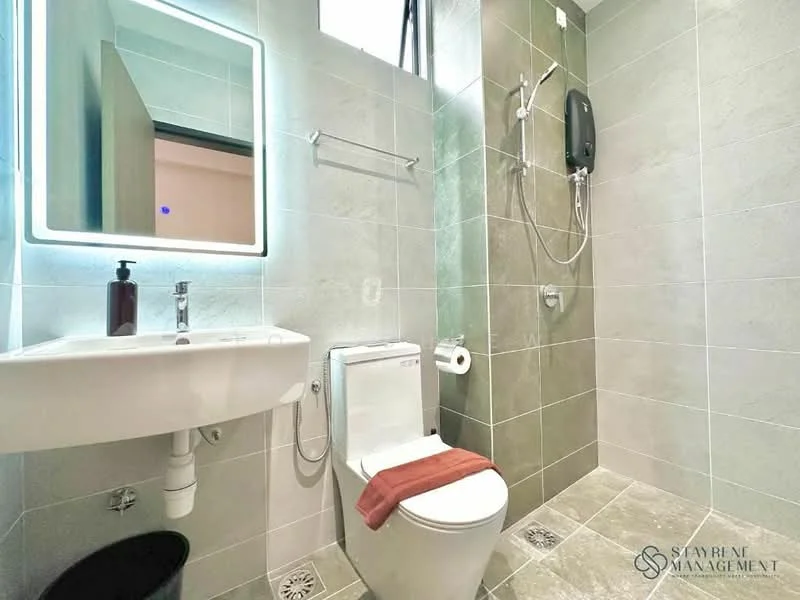 Bathroom features: wall-mounted toilet, single-sink vanity with wall-mounted mirror, chrome basin mixer faucet, shower with handheld shower head, wall-mounted water heater, grey ceramic tile walls, light grey floor tiles, towel rack, toilet paper holder, soap dispenser, orange bath towel; style: modern.