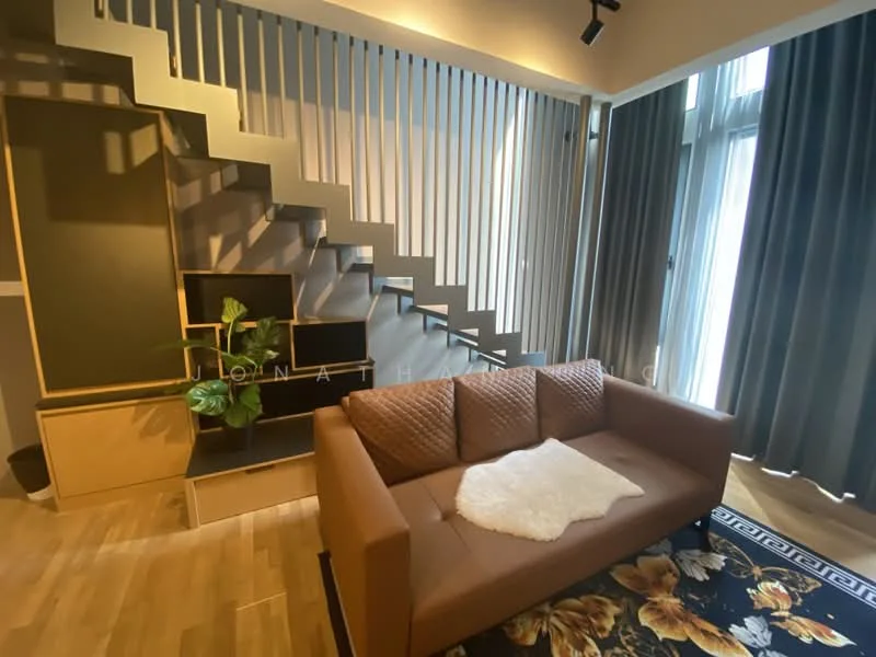 Living features: brown leather sofa, decorative throw blanket, area rug with floral pattern, wooden flooring, floor-to-ceiling windows, curtains, wall-mounted TV, open shelving unit, staircase with metal railing, indirect lighting; style: modern.