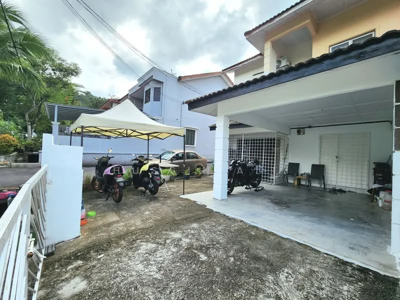 Exterior type: semi-detached house; features: covered car porch with awning, concrete flooring, two parked motorcycles, one parked car, manicured landscaping, surrounded by residential buildings, fenced perimeter, outdoor seating area, paved driveway; style: modern.