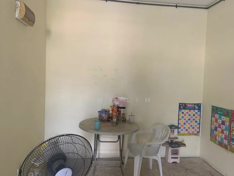 Room features: light yellow painted walls, tile flooring, round dining table, plastic chair, wall-mounted air conditioning unit, floor fan, colorful wall calendar, small table with snacks, green markings on wall.