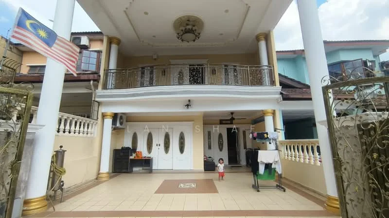 Exterior type: detached bungalow; features: white painted facade, two-storey structure, balcony with decorative railing, double main entrance doors, porch area with tiled flooring, decorative columns, flagpole with Malaysian flag, manicured front yard, outdoor laundry area with drying rack, paved driveway; style: modern.