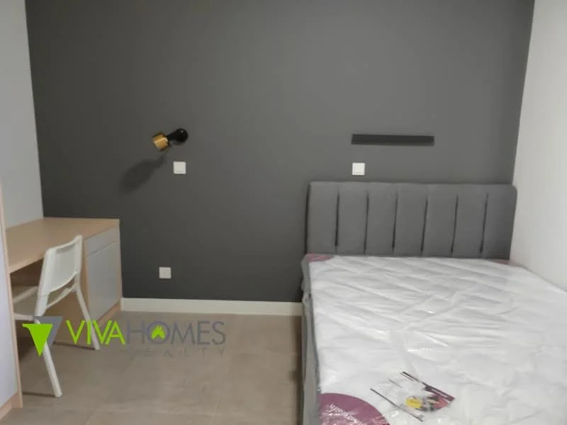Bedroom features: grey accent wall, white painted walls, queen-size bed with upholstered headboard, desk with chair, wall-mounted light fixture, tile flooring, window with no visible treatment, built-in shelving; style: modern.
