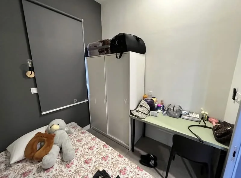 Bedroom features: single bed with floral bedding, grey accent wall, white wardrobe, desk with chair, window with roller blinds, decorative wall hook, various personal items on desk, stuffed animal on bed.