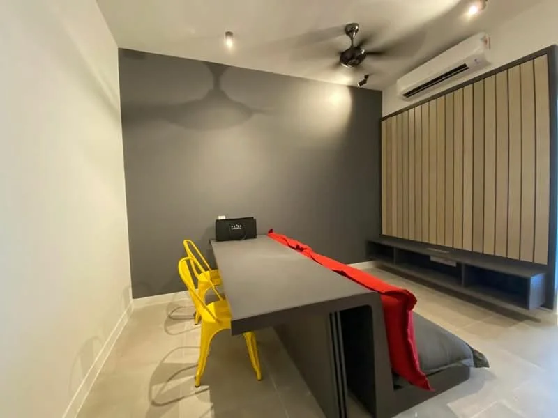 Room features: grey accent wall, white painted walls, tile flooring, ceiling fan, wall-mounted air conditioning unit, built-in storage unit with wood paneling, long table, two yellow chairs, red blanket or throw; style: modern.