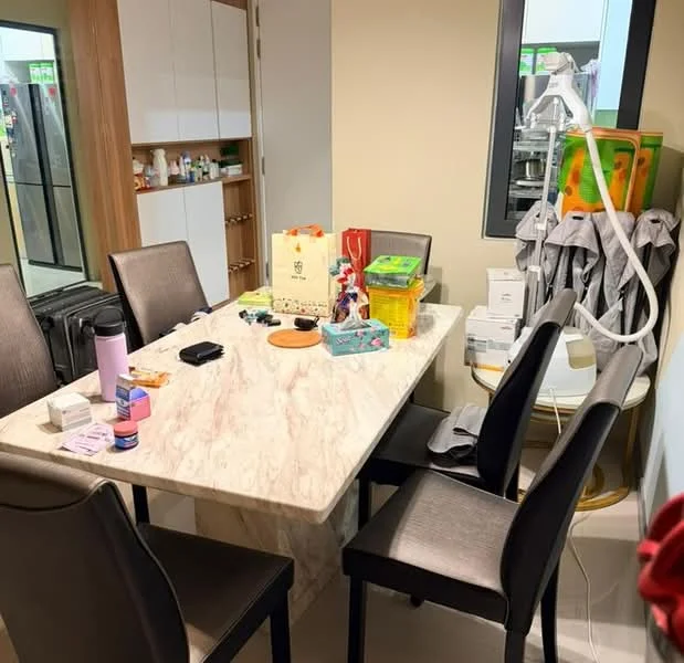 Dining features: marble dining table, 4 upholstered dining chairs in grey, wall-mounted cabinets, refrigerator visible in background, various items on table including bags and containers, decorative items on table, light-colored walls, tile flooring; style: modern.