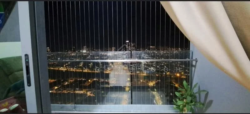 Room features: city skyline view, curtains, green plant, balcony railing, night lighting, window, sofa visible in background; view: city.